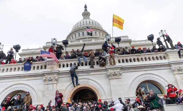 Supporters of former president Donald Trump are pictured scaling the walls of the U.S. Capitol Building on Jan. 6, 2021.