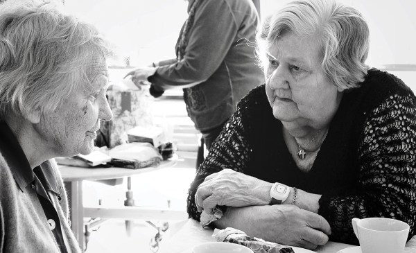 A photo of elderly women chatting at the table over the coffee.