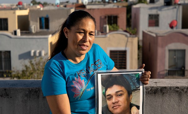 Above her home in Juarez, Nuevo León, Mexico, Elva Rivas holds a portrait of her husband, Roberto Maciel Ramírez, who disappeared in 2010.