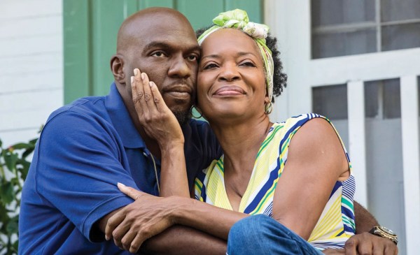 Hollywood Desonier, left, played by Omar J. Dorsey, sits on a porch next to on-screen squeeze Violet Bordelon (“Aunt Vi”), played by Tina Lifford, in Queen Sugar. Aunt Vi's is smiling as her hand cradles Hollywood's face.