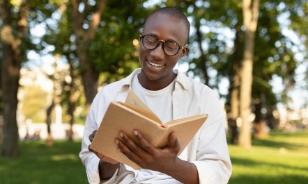 Student reading a book with nature in the background