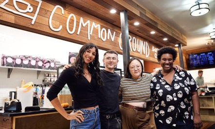 A team photo of various ethnicity people running their coffee shop, staring into camera.