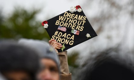 Demonstrator holds up a graduation cap that reads "Dreams Without Borders #DACAStrong"