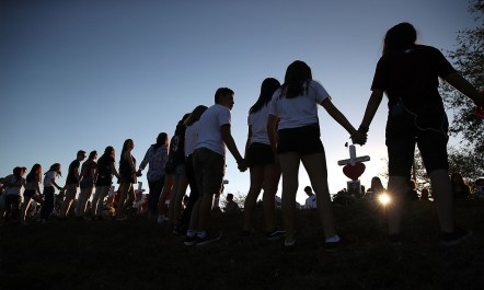 Photo of students holding hands at a vigil for a school shooting.